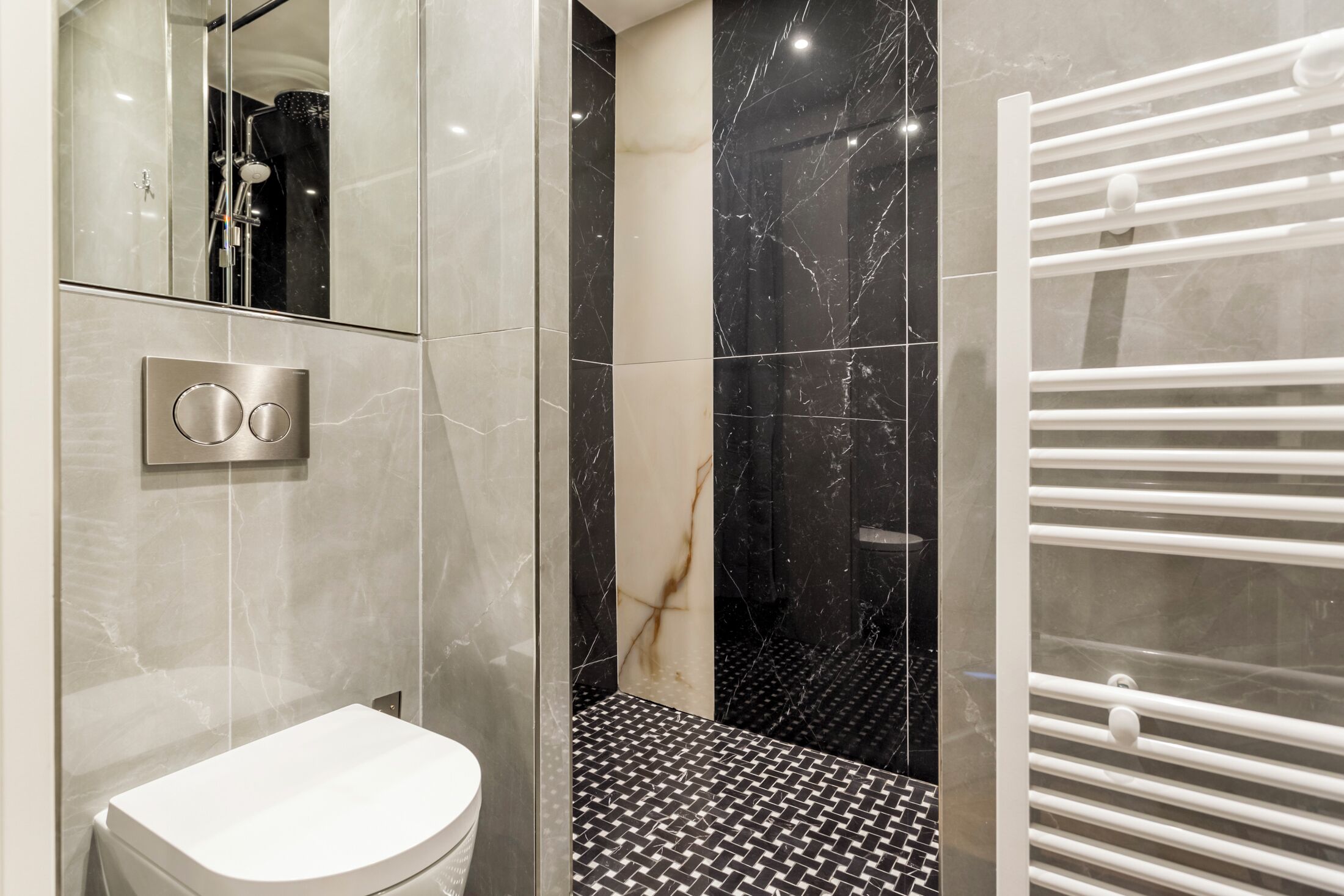 Un bagno moderno con un lavandino bianco, una cabina doccia in vetro e un pavimento a pavimento bianco e nero.