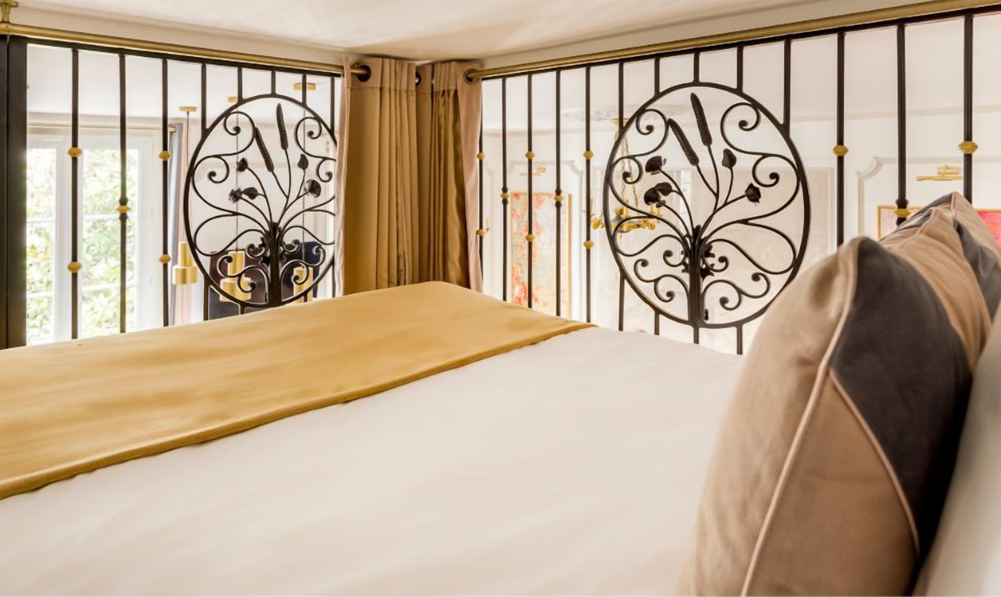 A bedroom with a bed, curtains, and decorative metal railings.