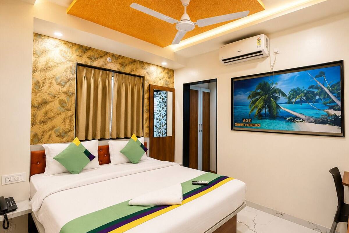 A hotel room with a bed, a ceiling fan, an air conditioning unit, a painting, and a marble floor.