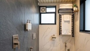 Ένα σύγχρονο μπάνιο με ντους, τουαλέτα και κρεμάστρα για πετσέτες.