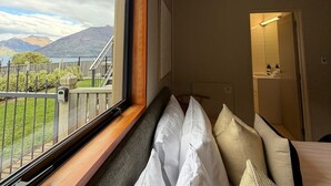 Habitación de hotel con un ventanal que ofrece vistas a montañas y un lago.