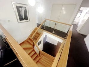 Ein modernes Interieur mit einer Holztreppe, einem Glastrennwerk und einer weißen Tür.