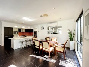 Una cocina moderna con una isla central, taburetes de bar, una mesa de comedor con sillas y un amplio ventanal con vistas.