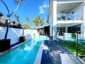 Ein modernes Haus mit Schwimmbad, Balkon und gepflegtem Garten.