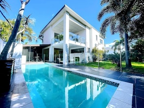 A modern house with a swimming pool, large windows, and a balcony.
