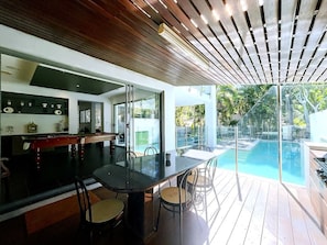 A modern kitchen with a glass dining area overlooking a swimming pool.