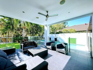 Eine Außenpatio mit Sitzgelegenheiten, einem Pool und einem Deckenventilator.