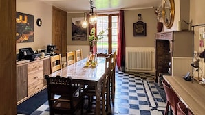 A dining area with a checkered floor, wooden table, chairs, and a kitchen area with appliances. - The Babouz Cottage, 4*,  entire house in the heart of Mirepoix and Cathars area (Mirepoix)