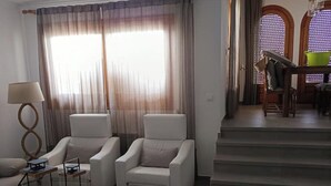 Un salon moderne comprenant un ensemble de canapés, une table basse et un escalier menant à un espace repas.