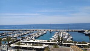 Un port de plaisance où sont amarrés de nombreux bateaux, un ciel dégagé et une vue sur la mer.