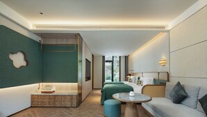 A modern hotel room with a bed, a sofa, a small table, and a TV.