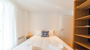 A hotel room with a neatly made bed, a wooden wardrobe, and a nightstand with a lamp. - Indigo Blue • Air conditioning - Swimming pool - Parking - Calm (La Garde-Freinet)