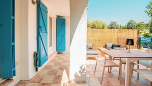 A patio with a table and chairs, a blue door, and a white wall. - Indigo Blue • Air conditioning - Swimming pool - Parking - Calm (La Garde-Freinet)