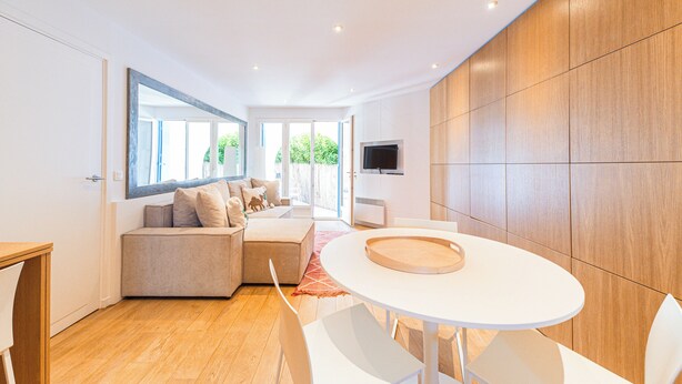 A modern living room with a white sofa, a round dining table, and a large window. - Indigo Blue • Air conditioning - Swimming pool - Parking - Calm (La Garde-Freinet)