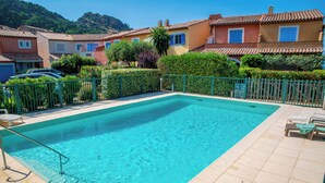 A rectangular swimming pool with a tiled deck, surrounded by a low green fence. - Indigo Blue • Air conditioning - Swimming pool - Parking - Calm (La Garde-Freinet)