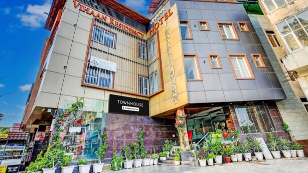 A modern building with 'VIAHAN RESIDENCY HOTEL' signage, a 'TOWNHOUSE' label, and multiple potted plants in front. - Deluxe Hotel Vihaan Residency (Dera Bassi)