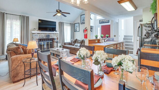 A spacious living area with a fireplace, a dining table set with chairs, and a television mounted on the wall. - Steps to Jack Frost Ski Resort: Townhome w/ Decks (Lake Harmony)