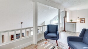 A spacious living area with a high ceiling and a balcony. There are two blue armchairs and a coffee table with decorative items. - Steps to Jack Frost Ski Resort: Townhome w/ Decks (Lake Harmony)