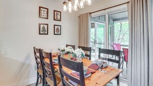 A dining area with a wooden table set for four, surrounded by chairs, with a view of greenery outside. - Steps to Jack Frost Ski Resort: Townhome w/ Decks (Lake Harmony)