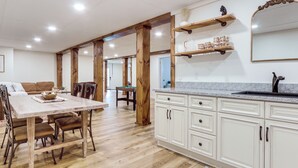 Une cuisine spacieuse avec des poutres en bois, un coin repas avec une table et des chaises, et un grand miroir au-dessus de l’évier.