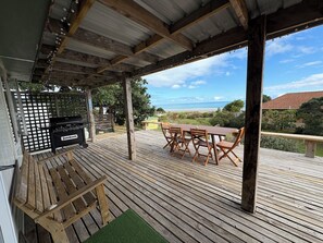 Outdoor dining - Watch the waves from the large, sunny deck of this 1950's bach. Pet friendly. (Ahipara)