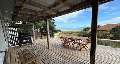 Watch the waves from the large, sunny deck of this 1950's bach. Pet friendly.