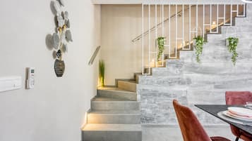 Una escalera moderna con un muro de piedra, un área de comedor con mesa y sillas, y un termostato fijado a la pared.