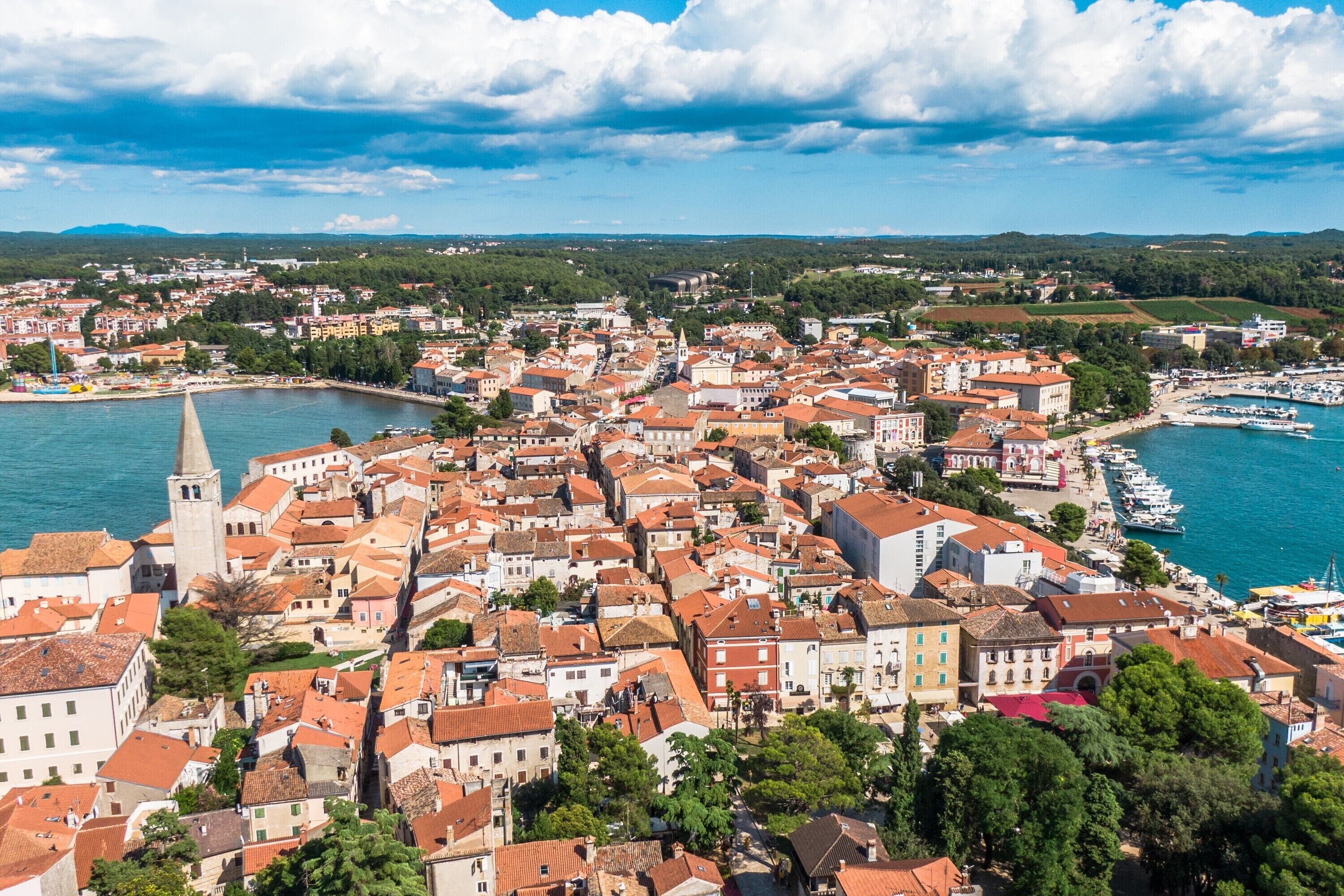 A coastal town with historic buildings, a prominent church tower, and a marina.