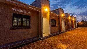 A row of buildings with external lighting, a paved walkway, and a clear sky. - The Den Soroti Green (Soroti)