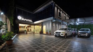 A modern hotel with a geometric patterned entrance, a well-lit facade, and several parked cars. - Hotel Afotel Mumbai-Near International Airport (Mumbai)