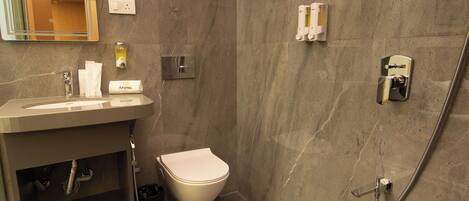 A modern bathroom with a marble wall, a white toilet, a sink with a mirror, and a shower area.