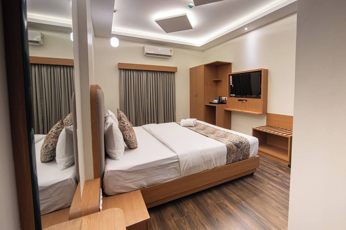 A modern hotel room with a wooden bed, a flat-screen TV, and built-in storage.