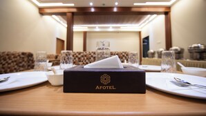 A hotel dining area with a table set for a meal, a tissue box labeled "AFOTEL" on the table, and a patterned wall in the background. - Hotel Afotel Mumbai-Near International Airport (Mumbai)