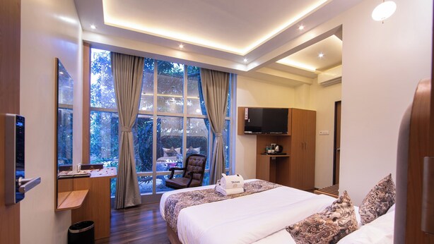 A modern hotel room with a large bed, a desk, a chair, and a TV. - Hotel Afotel Mumbai-Near International Airport (Mumbai)