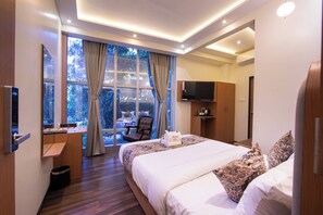 A modern hotel room with a large bed, a desk, a chair, and a TV.