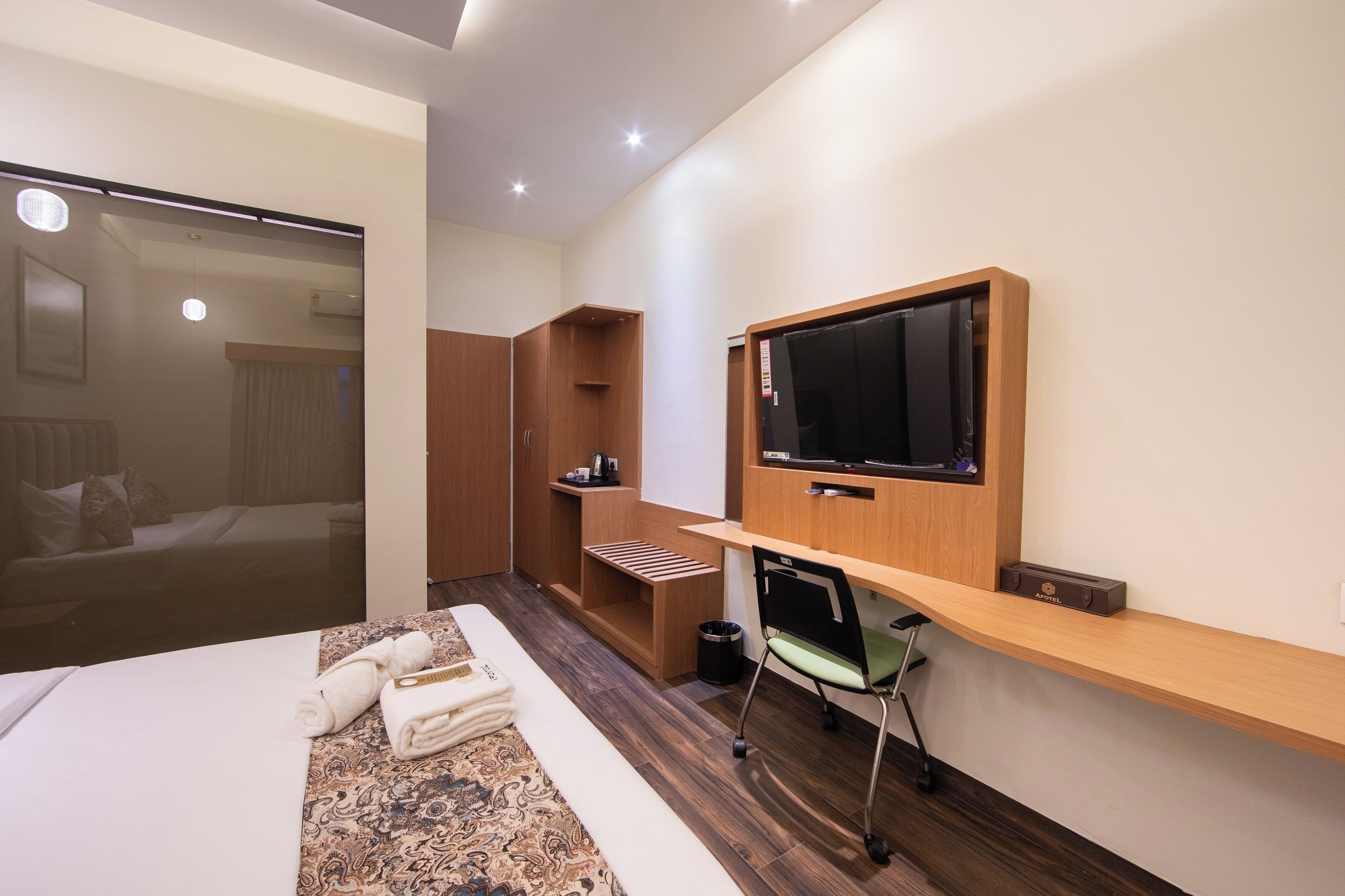 Una camera d'albergo moderna con un letto, una scrivania con un computer, una TV e un armadio.