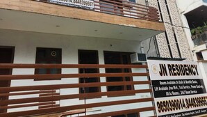 A multi-story building with balconies and a sign advertising rooms available on daily and monthly basis, including amenities like lift, free Wi-Fi, taxi service, power backup, and 24x7 room service. - JN RESIDENCY (Gurugram)
