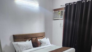 A neatly arranged bedroom with a bed, a small round table, and a window with curtains. - JN RESIDENCY (Gurugram)