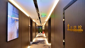 A corridor with a carpeted floor, a digital display on the left, and a fire hose reel sign on the right. - kunningyuehaojiudian (Kunming)