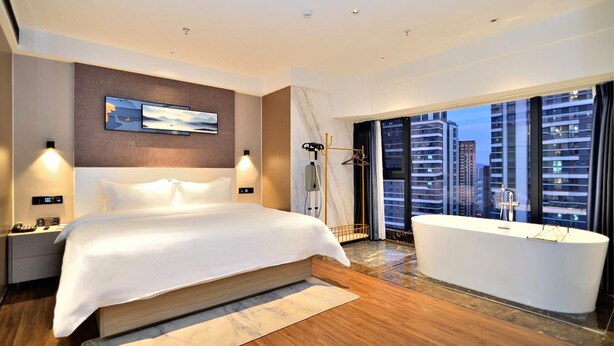 A modern hotel room with a large bed, a bathtub, and a city view. - kunningyuehaojiudian (Kunming)