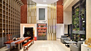 A modern interior with a dining area, seating, and a bookshelf with plants. - kunningyuehaojiudian (Kunming)