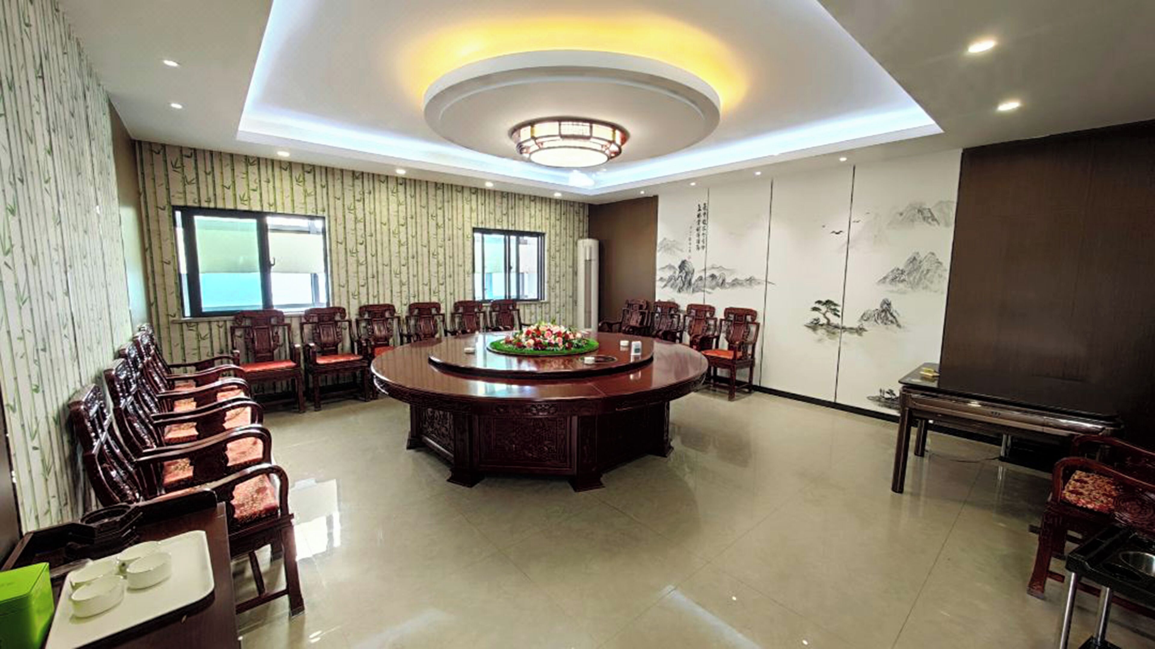 A conference room with a round table, chairs, a television, and a decorative wall.