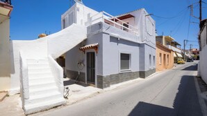 A narrow street with a white building featuring a staircase leading to a balcony. - Galatas Maisonette (Galatas)