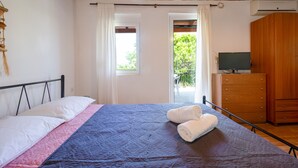 A bedroom with a bed, a wooden dresser, and a television on a dresser. - Galatas Maisonette (Galatas)