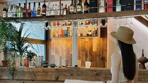 A bar area with a wooden counter, shelves of liquor bottles, and hanging wine glasses. - Ayata Hotel (Chengdu)