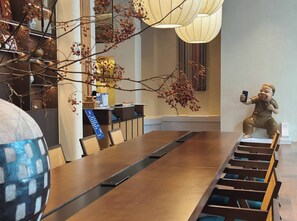 Une salle de conférence avec une longue table, des chaises et une statue représentant une personne prenant un autoportrait.