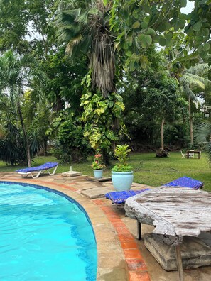 A swimming pool with lounge chairs and a wooden deck. - Perfect 3-bedroom apartment with AC in superb Mtwapa location (Mtwapa)