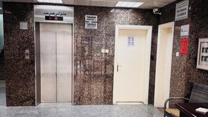 Un espace d’ascenseur avec des murs en granit, un comptoir d’accueil et une porte avec une pancarte.