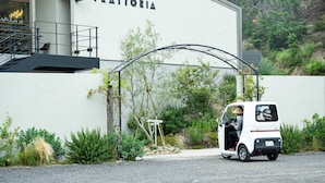 Un edificio blanco con un letrero que dice "TRATTORIA" y un coche blanco estacionado adelante.