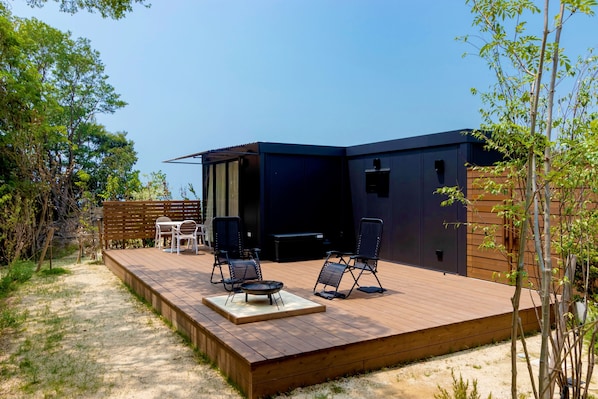 A modern outdoor deck with a built-in barbecue, two lounge chairs, and a small table.